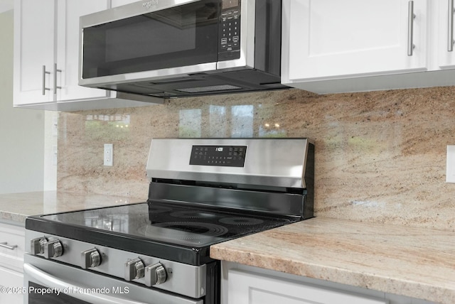 kitchen featuring stainless steel appliances, white cabinets, and backsplash