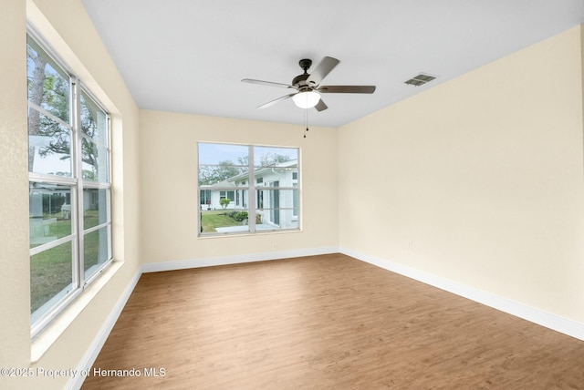 spare room with wood finished floors, visible vents, and a healthy amount of sunlight