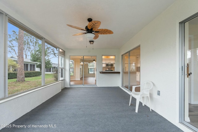 unfurnished sunroom featuring a ceiling fan