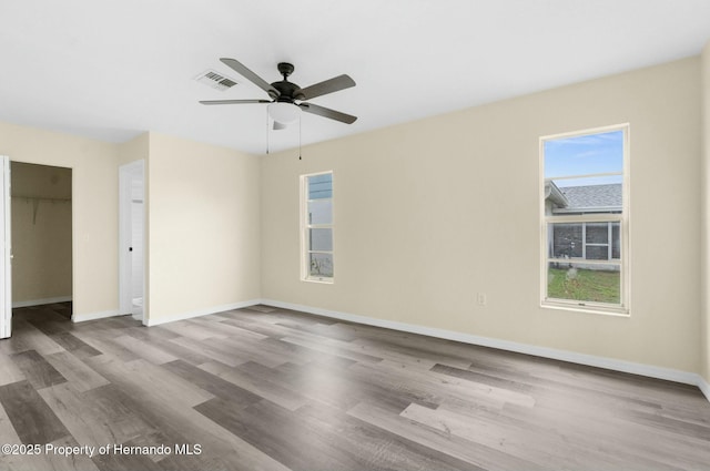 unfurnished bedroom with multiple windows, visible vents, and wood finished floors