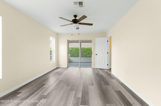 empty room featuring visible vents, ceiling fan, baseboards, and wood finished floors