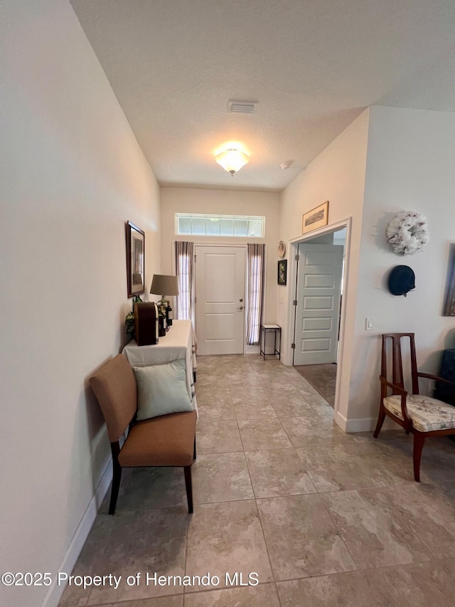 entrance foyer featuring baseboards, visible vents, and a textured ceiling