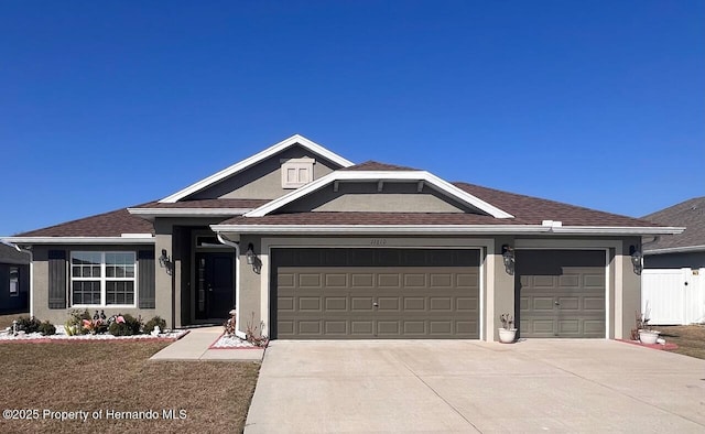 ranch-style house featuring a garage, driveway, and stucco siding