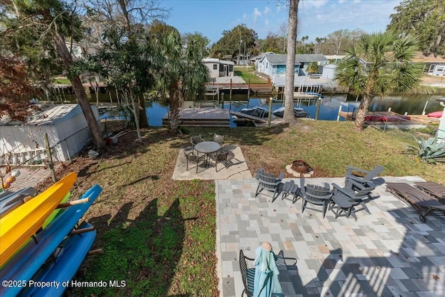 view of yard featuring a water view, a patio area, a dock, and a fire pit