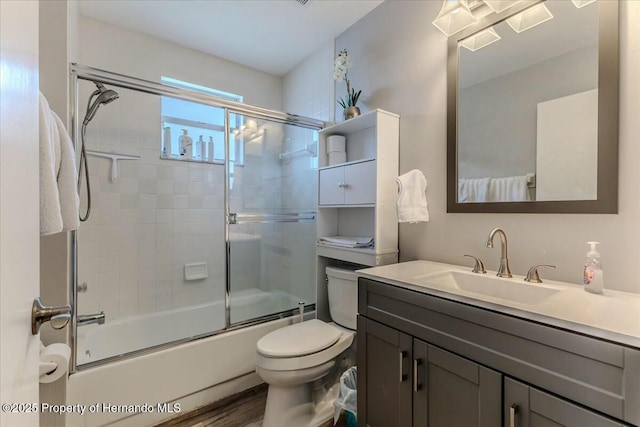 bathroom featuring combined bath / shower with glass door, vanity, toilet, and wood finished floors