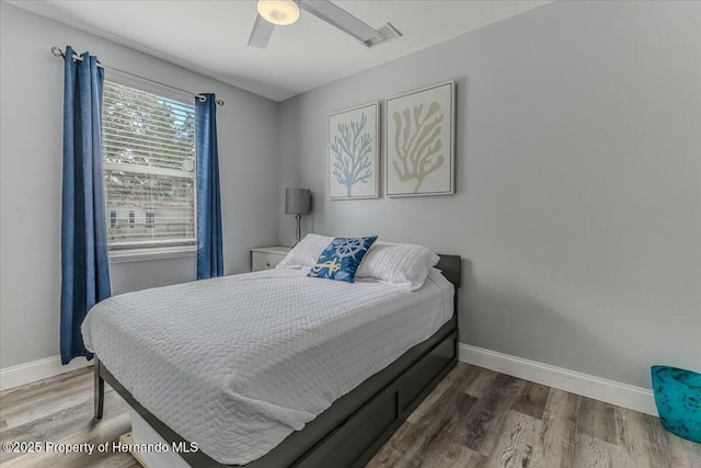 bedroom with ceiling fan, visible vents, baseboards, and wood finished floors