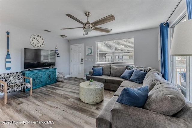 living room with visible vents, wood finished floors, a ceiling fan, and baseboards