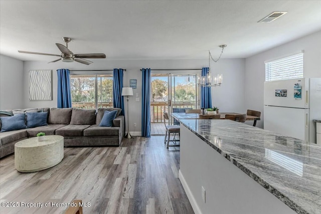 kitchen with plenty of natural light, open floor plan, decorative light fixtures, freestanding refrigerator, and light stone countertops