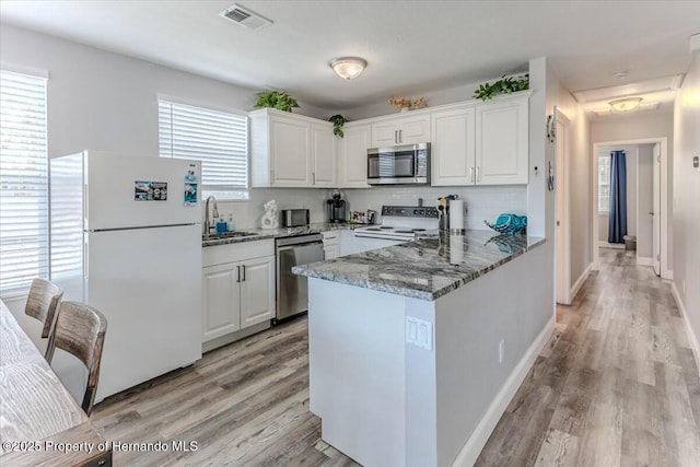 kitchen featuring a peninsula, white cabinetry, visible vents, and appliances with stainless steel finishes