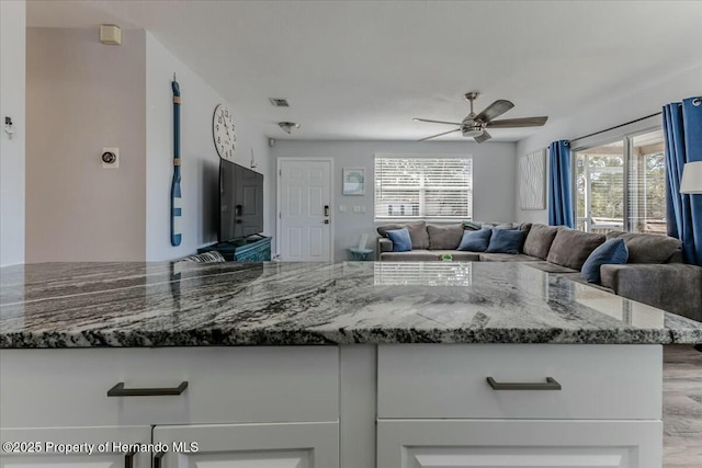 kitchen featuring stone countertops, visible vents, and white cabinets