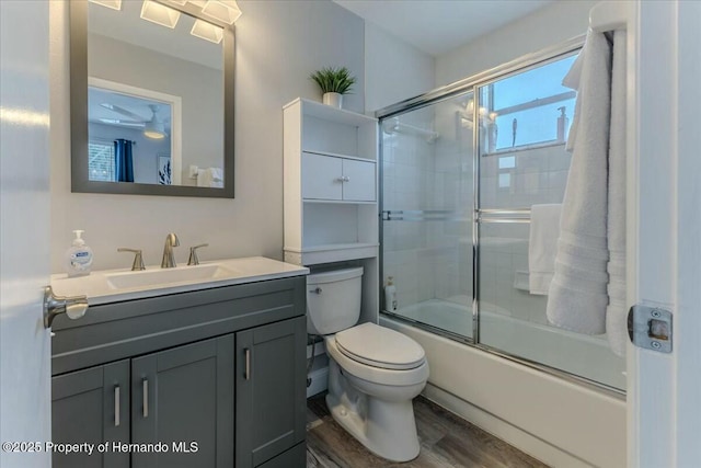 full bathroom with toilet, bath / shower combo with glass door, wood finished floors, and vanity