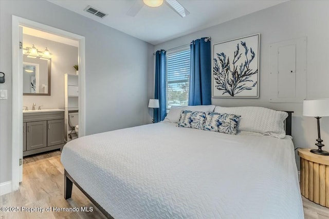 bedroom featuring a sink, visible vents, a ceiling fan, light wood-type flooring, and ensuite bath