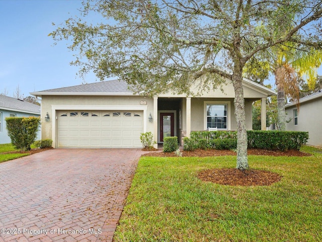 ranch-style home with a garage, a front yard, decorative driveway, and stucco siding