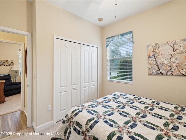 bedroom featuring light carpet, ceiling fan, a closet, and baseboards