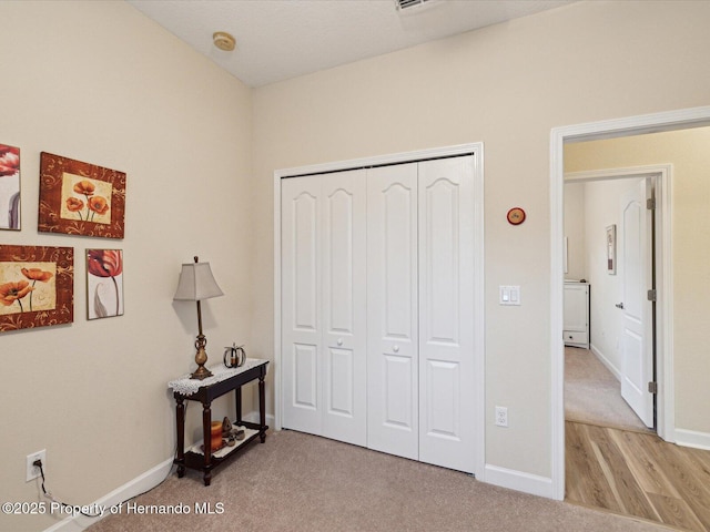 bedroom featuring a closet, light colored carpet, and baseboards