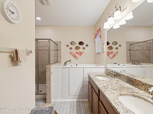 full bathroom featuring double vanity, a sink, a shower stall, and a bath