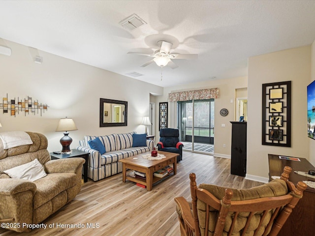 living room with a ceiling fan, visible vents, and light wood-style floors