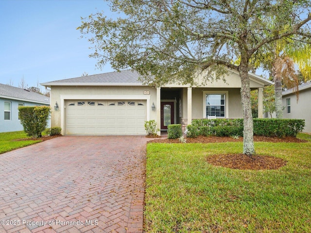 ranch-style home featuring an attached garage, a front yard, decorative driveway, and stucco siding