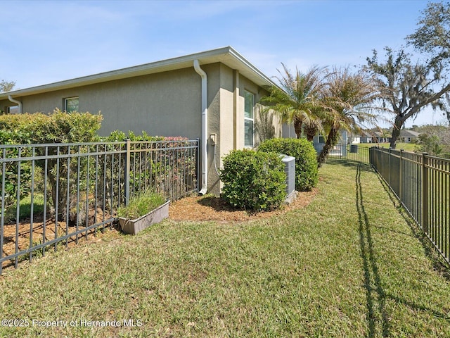 view of side of home featuring a yard, fence, and stucco siding