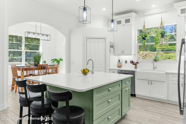 kitchen with light countertops, green cabinets, white cabinetry, a sink, and dishwasher