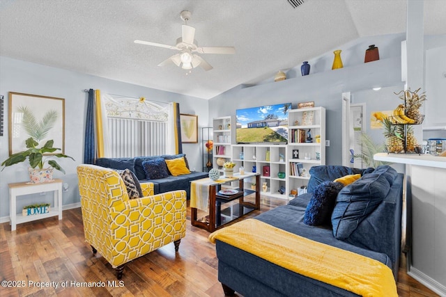 living area with a textured ceiling, wood finished floors, a ceiling fan, baseboards, and vaulted ceiling