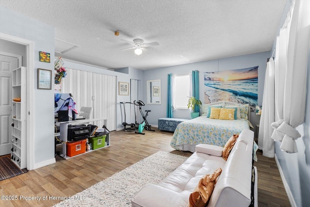 bedroom featuring a textured ceiling, ceiling fan, wood finished floors, and baseboards