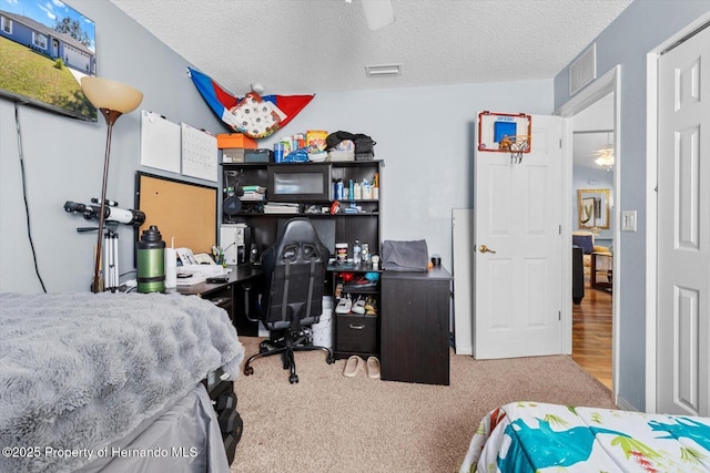 bedroom with a textured ceiling, ceiling fan, visible vents, and light colored carpet