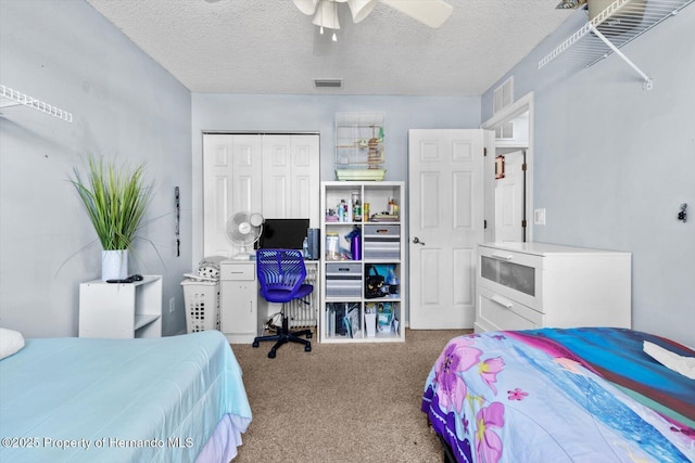 carpeted bedroom featuring a ceiling fan, a closet, visible vents, and a textured ceiling