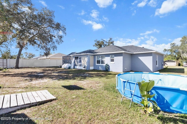 back of house with a fenced in pool, roof with shingles, stucco siding, a lawn, and fence