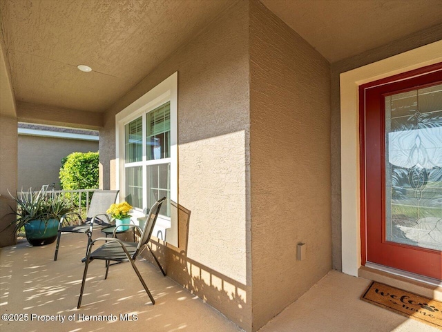 view of exterior entry with a porch and stucco siding