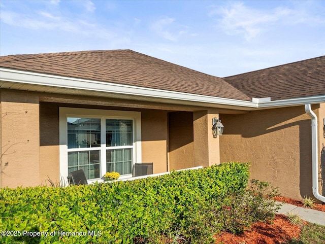 property entrance featuring roof with shingles and stucco siding