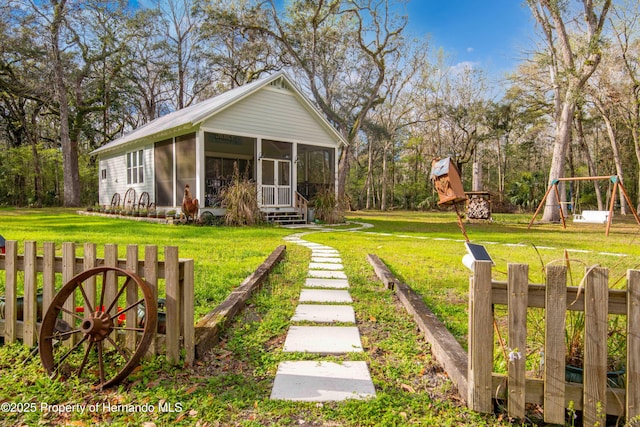 exterior space with a sunroom, a front lawn, and a playground