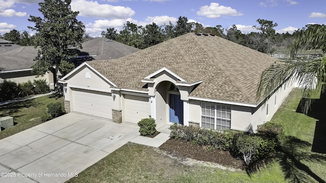 ranch-style house featuring an attached garage, a shingled roof, concrete driveway, and stucco siding