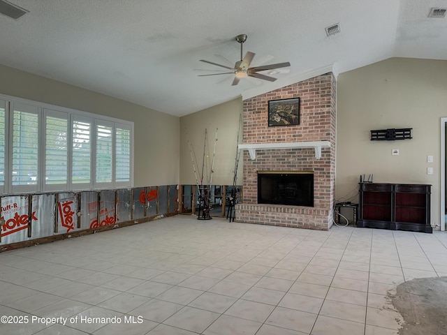 living area with light tile patterned floors, lofted ceiling, visible vents, a brick fireplace, and a textured ceiling