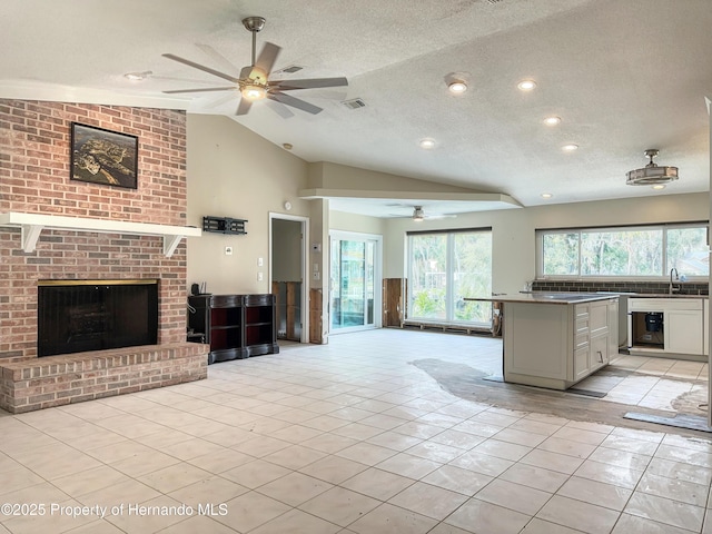 kitchen featuring open floor plan, light tile patterned flooring, a fireplace, and white cabinets