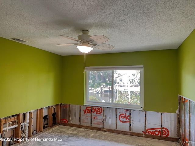 spare room featuring a ceiling fan, visible vents, and a textured ceiling