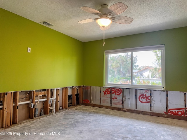 spare room featuring visible vents, unfinished concrete flooring, a textured ceiling, and ceiling fan