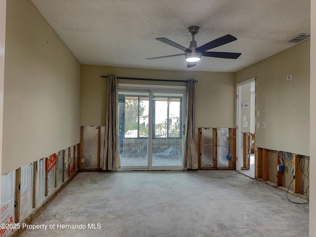 spare room featuring a ceiling fan, visible vents, a textured ceiling, and unfinished concrete floors