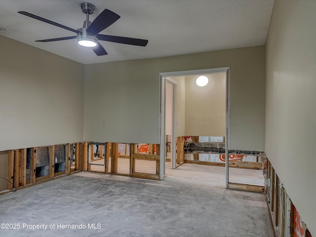 spare room with a ceiling fan and unfinished concrete floors