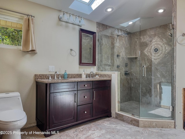 full bath with a sink, a skylight, a shower stall, and toilet