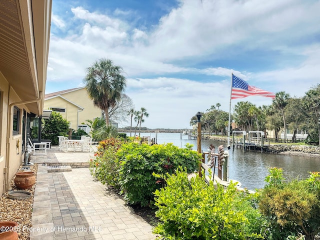 view of patio featuring a water view, boat lift, and a dock