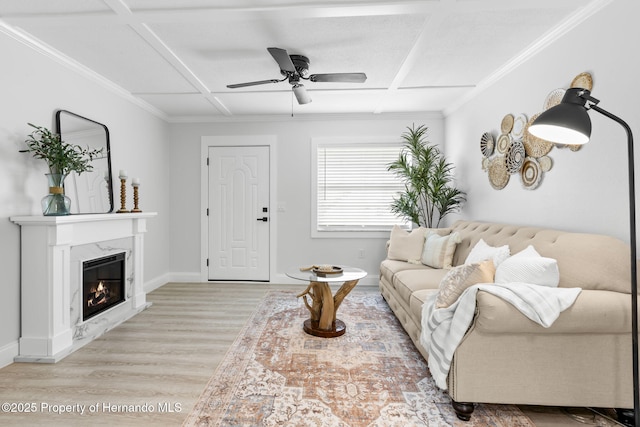 living room featuring ceiling fan, a premium fireplace, coffered ceiling, and light wood-style flooring