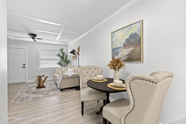 interior space with baseboards, ornamental molding, a ceiling fan, and light wood-style floors