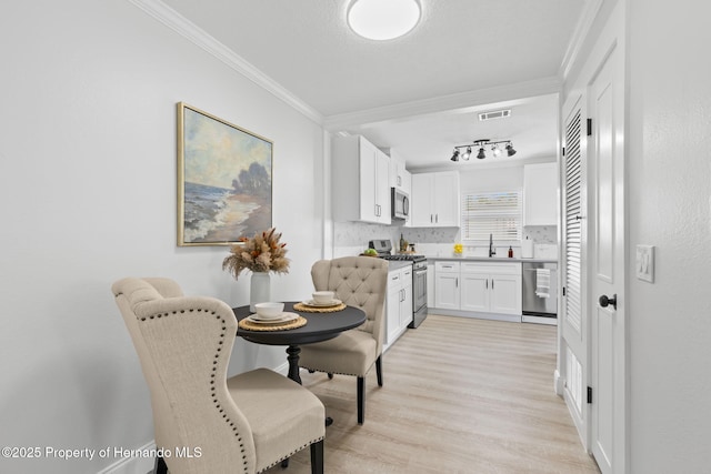 kitchen featuring stainless steel appliances, visible vents, white cabinetry, light countertops, and crown molding