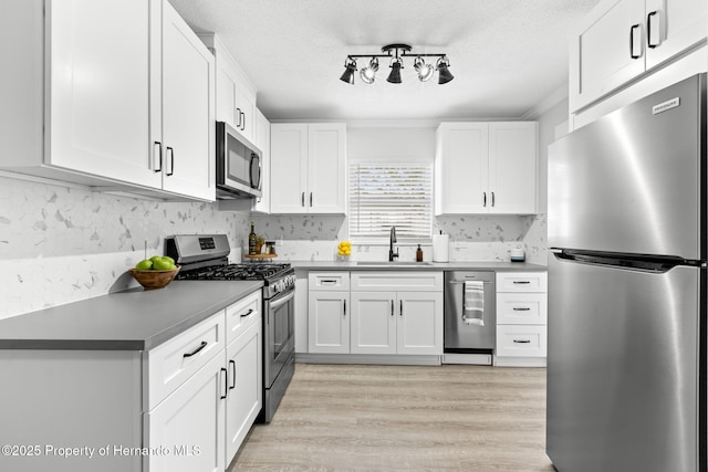 kitchen with stainless steel appliances, a sink, and white cabinetry