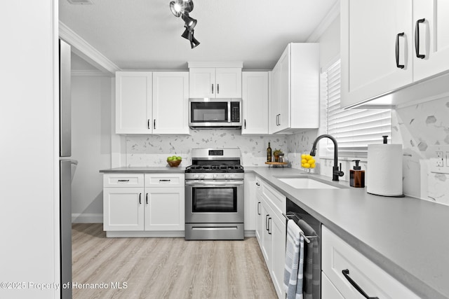 kitchen with light countertops, appliances with stainless steel finishes, a sink, and white cabinetry