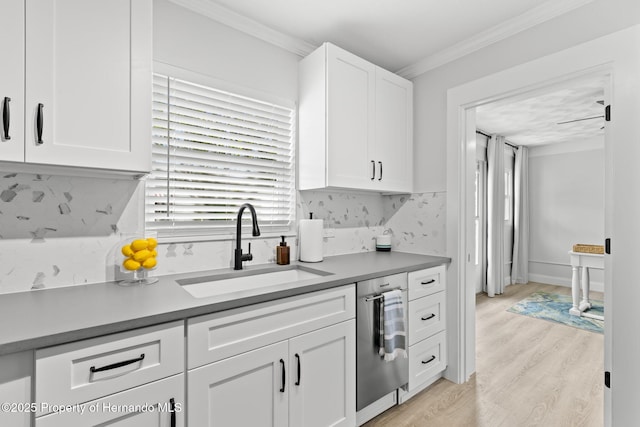 kitchen featuring crown molding, tasteful backsplash, white cabinetry, a sink, and light wood-type flooring