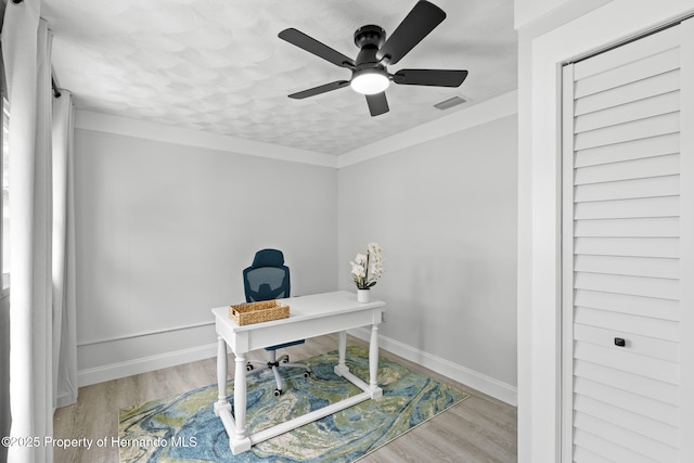 office space featuring baseboards, visible vents, crown molding, and light wood finished floors