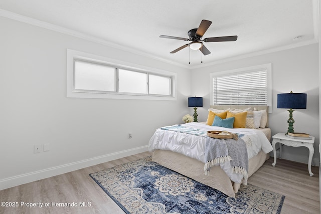 bedroom featuring ornamental molding, light wood-type flooring, ceiling fan, and baseboards