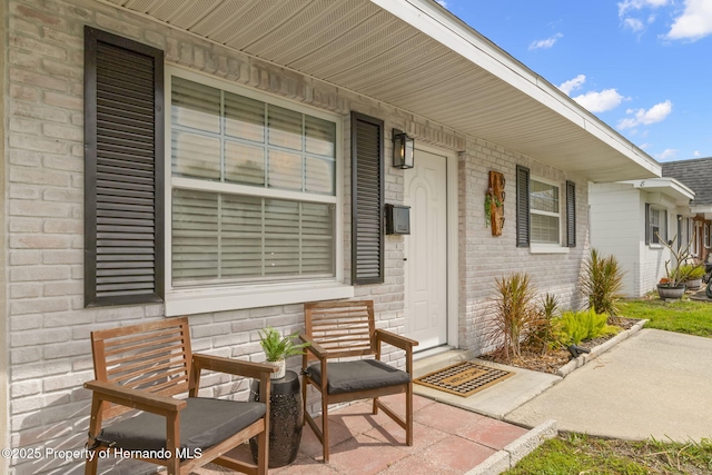 entrance to property with brick siding and a porch